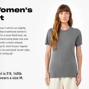May include: A dark grey short-sleeved t-shirt with a crew neckline. The image includes text regarding fit, stating: Women's Fit. Our unisex t-shirts run slightly larger than traditional women's sizes. Model is 5'8, 140lb and wears a size M.