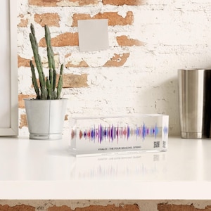 Könnte beinhalten: Ein klarer Acrylblock mit einem bunten Schallwellendesign im Inneren. Der Text "VIVALDI - THE FOUR SEASONS - SPRING" ist auf der Unterseite des Blocks aufgedruckt.