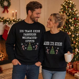 Op de afbeelding: Twee zwarte sweaters met ronde hals, witte tekst en kerstafbeeldingen. De linker sweater bevat de tekst "ICH TRAGE KEINE PASSENDEN WEIHNACHTS-OUTFITS" met een kerstboom en zuurstokken. De rechter sweater toont de tekst "ABER ICH SCHON!" met een boom.