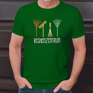 Può includere: Una maglietta verde con una grafica di tre rastrelli di diversi colori e il testo "RECHZENZENTRUM".