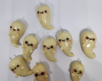 May include: Nine handmade clay ghost charms with painted faces and blush cheeks. Each ghost has a silver loop for hanging.