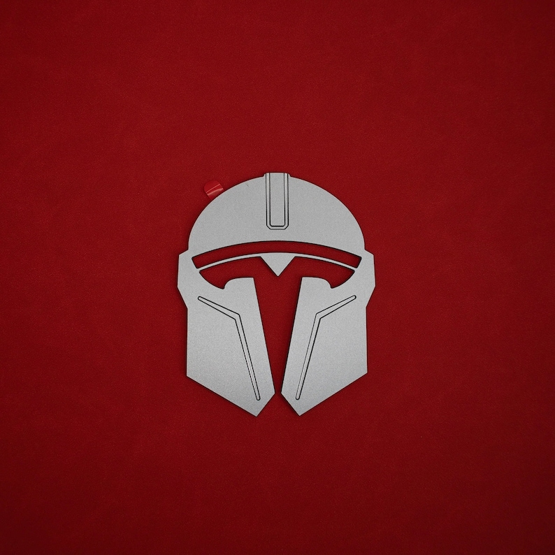 May include: A silver-colored Mandalorian helmet design against a solid red background. The helmet has a distinctive T-shaped visor and angular features. A small red accent is visible near the top left corner.
