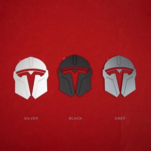May include: Three stylized helmet designs in silver, black, and grey, each with a red accent. The helmets are displayed against a vibrant red background. The word "SILVER", "BLACK", and "GREY" are written below each helmet.
