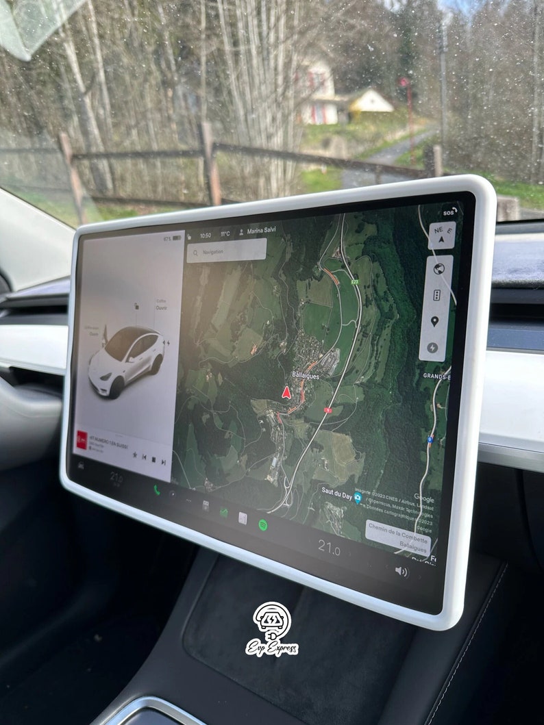 K&ouml;nnte beinhalten: Ein wei&szlig;er Tesla Model 3 mit einem gro&szlig;en Touchscreen-Display, das eine Karte eines bergigen Gebiets mit dem Text "Marina Salvi" und "Saut du Day" zeigt. Der Bildschirm zeigt auch einen digitalen Geschwindigkeitsmesser mit der Anzeige 21.0.