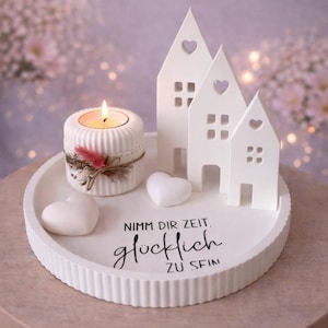 May include: A white ceramic tray with a candle holder, three house-shaped decorations, and two heart-shaped decorations. The candle holder has a lit candle and is decorated with lace and feathers. The tray has the text "Nimm dir Zeit, gl&uuml;cklich zu sein."