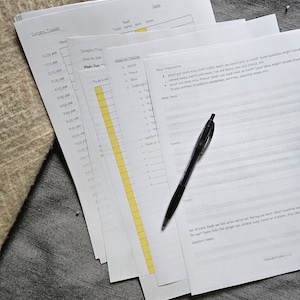 Puede incluir: Una hoja de papel blanca con un bolígrafo negro encima. El papel tiene una lista de verificación para la recuperación de la cirugía, que incluye secciones para comida, inodoro, agua, caminar y notas. La lista de verificación incluye horas de 12:00 AM a 5:00 AM. El papel también tiene una sección para "Hospital Packing" con una lista de artículos para empacar, que incluyen "billetera", "llaves", "supervisión", "comodidad" y "libro o diario".