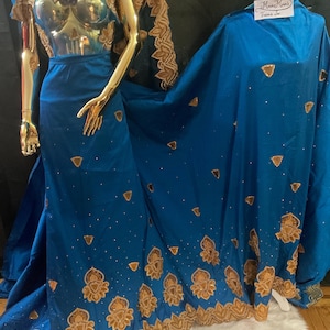 May include: A vibrant blue gown and matching fabric drape featuring intricate gold embroidery along the hemlines and scattered gold triangular accents. The fabric is embellished with small silver beads throughout. A tag reads "Mma Mma's Treasures".