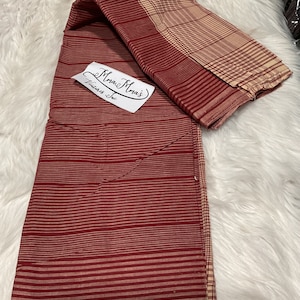 May include: Red and cream striped fabric with a cream and red plaid fabric folded on top. The fabric has a label that says "Mama Mia's Fabrics Inc."