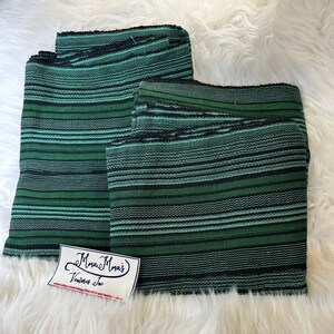 May include: Two pieces of green and black striped fabric. The fabric is woven with a textured pattern. The fabric is folded in half and a small white label with the text "Mama Mma's Vintage Inc" is attached to the fabric.