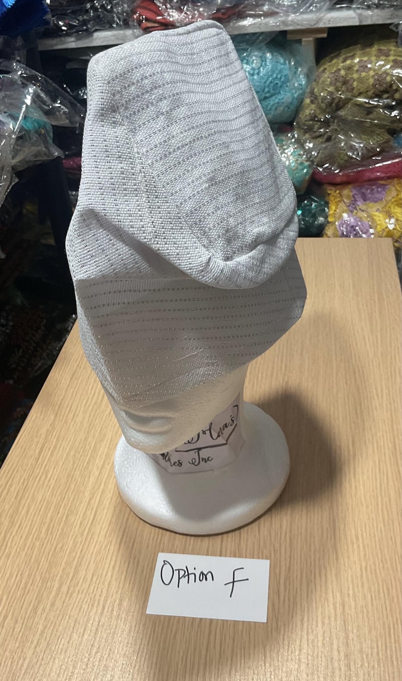 May include: A light gray, textured hat displayed on a white mannequin head. The hat has a slight sheen and a horizontal striped pattern. A small white card with "Option F" is in front of the mannequin.