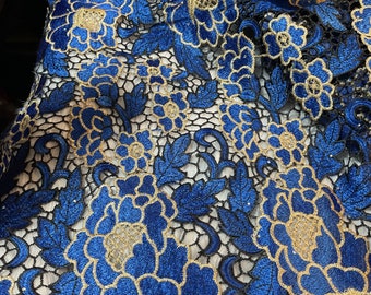 May include: Blue and gold floral lace fabric with a delicate pattern. The lace has a shiny finish and is perfect for crafting or sewing projects.