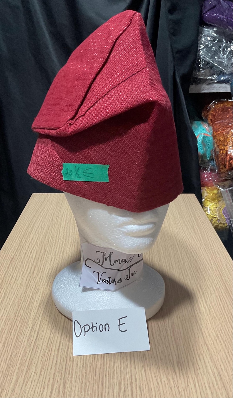 May include: A red fabric hat with a folded brim, displayed on a white mannequin head. The hat has a textured appearance. A green sticker indicates a measurement of 23 1/2 inches. A label below reads "Option E."