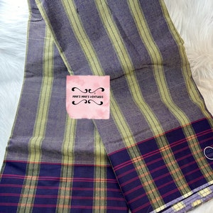 May include: A purple and yellow striped fabric with a red and yellow plaid border. The fabric is folded in half and has a small tag that says "MMA'S MIA'S VENTURES".