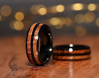 May include: Two black and brown wood inlay rings. The rings have a polished black finish and two thin strips of wood inlay.