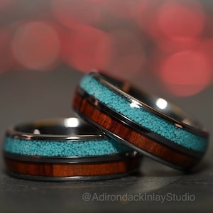 May include: Two matching wedding bands with a black tungsten carbide base, a brown wood inlay, and a turquoise stone inlay. The rings are stacked on top of each other. @AdirondackInlayStudio