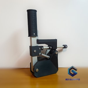 Op de afbeelding: Een zwart-zilveren 3D-geprinte handrem met een hendel en een veer. De handrem is gelabeld met "DRIFT-1".