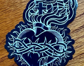May include: A black and white sticker of a heart with a crown of thorns, a cross, and flames. The heart is dripping with blood.