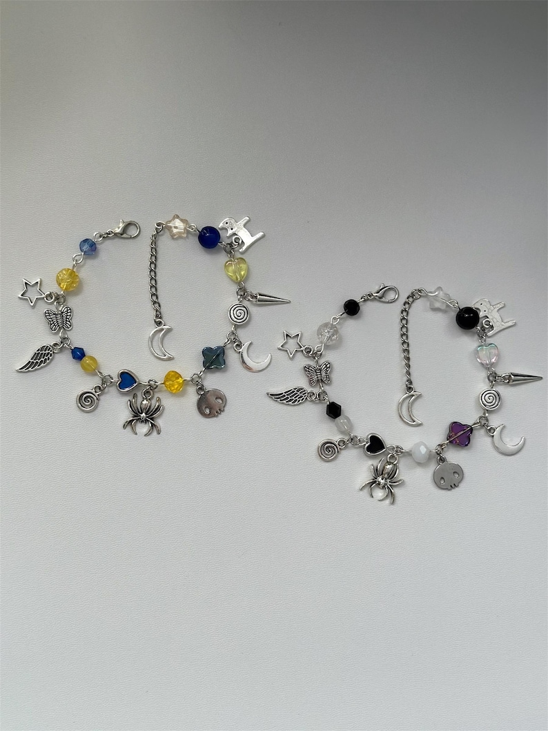 May include: Three silver charm bracelets with colorful beads and charms, including stars, moons, hearts, wings, spiders, and a unicorn.
