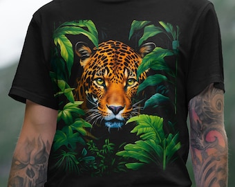 Puede incluir: Camiseta negra con una ilustración detallada de la cara de un jaguar rodeada de hojas verdes. El jaguar tiene manchas naranjas y negras y ojos amarillos. El diseño es una imagen llamativa.