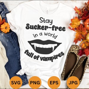 Peut inclure: T-shirt blanc avec un texte noir qui dit "Stay Sucker-free in a world full of vampires". Le texte est dans un style de police rétro. Une bouche de vampire noire avec des crocs se trouve sous le texte.