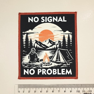 May include: A square fabric patch with a red border featuring a black and white camping scene with an orange sun, a person sitting on a log, a tent, and a campfire. The text reads NO SIGNAL NO PROBLEM. A ruler shows the patch is 9 cm wide.