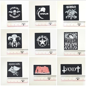 Pode incluir: Nove patches em preto e branco com vários logotipos e textos de bandas. Os patches incluem designs com caveiras, um elefante, uma estrela e outros gráficos. Cada patch tem aproximadamente 7,6 cm de largura.