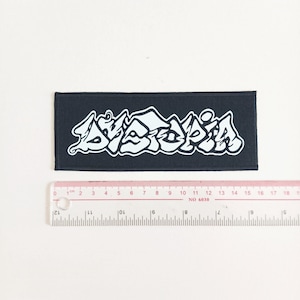 May include: Black fabric patch with the white text "AMATOPIA" in a stylized font.