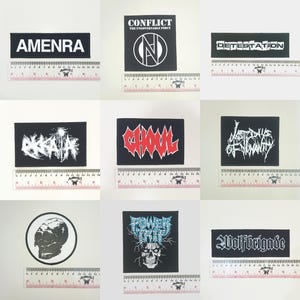 Peut inclure: Ensemble de neuf écussons noirs avec texte et graphiques blancs ou rouges. Les écussons présentent des noms et logos de groupes, dont "Amenra", "Conflict" et "Ghoul". Chaque écusson est rectangulaire ou circulaire, avec une règle.