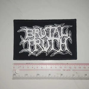 May include: Black and white embroidered patch featuring the band name "Brutal Truth" in a stylised font.