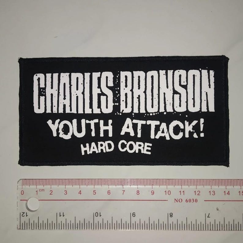 May include: Black and white embroidered patch with the text "CHARLES BRONSON YOUTH ATTACK! HARD CORE".