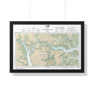 May include: A framed nautical chart titled Coosaw and Broad Rivers, featuring detailed blue waterways, tan landmasses, and green vegetation areas. The map includes navigational data, depth soundings in feet, and a black frame border.