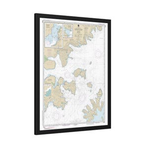 May include: A black framed nautical chart of the Southwestern Approaches to the English Channel. The chart includes detailed information about the coastline, islands, and waterways. The chart is printed on a white background with blue and brown lines and text.