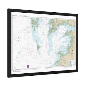 May include: A framed nautical chart of the Chesapeake Bay featuring detailed hydrographic data, depth soundings, and navigational markers in shades of blue, tan, and green, enclosed within a simple black rectangular frame.