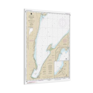 May include: A nautical chart of Keweenaw Bay, with detailed information on depths, shorelines, and navigational aids. The chart features a beige background with blue and white details, and is framed in white.