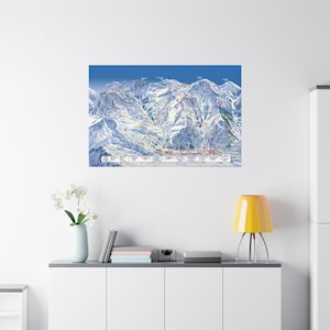 May include: A framed print of a ski resort map, featuring detailed trails and mountain terrain. The map is set against a blue sky backdrop, with white snow-covered peaks. The print is displayed on a white wall above a white cabinet.