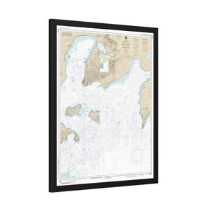 May include: A nautical chart of the waters around Sheep Island and Penobscot Bay, Maine. The chart is printed on paper and framed in black. The chart shows depths, buoys, and other navigational information.