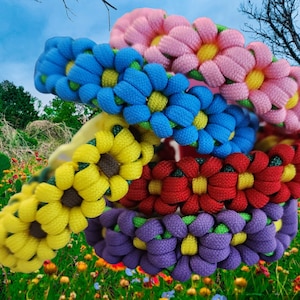 Puede incluir: Cinco pulseras de amistad coloridas con diseños de flores. Las pulseras están hechas de paracord tejido y presentan diferentes colores, incluyendo rosa, azul, amarillo, rojo y morado.