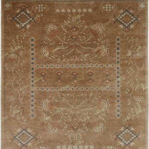May include: A rectangular, brown rug with an intricate pattern. The design features diamond shapes, floral motifs, and geometric borders in shades of beige, blue, and red. The words "Rugs Gallery" are repeated throughout the design.