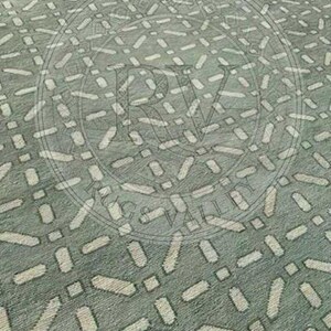 May include: A close-up view of a patterned rug. The rug has a light green background with a repeating pattern of off-white, elongated shapes and small squares. The design creates a textured appearance.