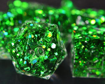 May include: Close-up of a set of green glitter dice. The dice are various shapes, including a twenty-sided die and a six-sided die. The dice are filled with green glitter and small colorful flecks.
