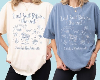 May include: Two t-shirts, one ivory and one blue, each with the text "Last Sail Before the Veil" and "Emily's Bachelorette" in a script font. The design includes nautical and beach-themed illustrations. The shirts are paired with black shorts.