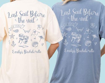 May include: Two t-shirts, one ivory and one blue, feature the text "Last Sail Before the Veil" with nautical-themed illustrations and "Emily's Bachelorette" below. The ivory shirt has a blue jean design, while the blue shirt has an ivory design.