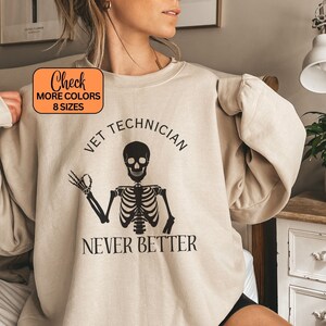 May include: Beige crewneck sweatshirt featuring the text "VET TECHNICIAN" above a skeleton graphic, and "NEVER BETTER" below. The sweatshirt has a round neckline and long sleeves. An orange box in the upper left corner says "Check MORE COLORS 8 SIZES".
