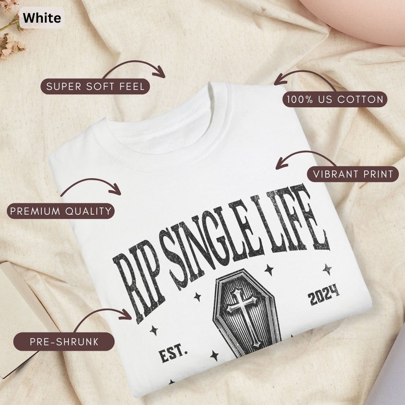 May include: White crew neck t-shirt with the text "RIP SINGLE LIFE" above a coffin graphic and the year 2024. The shirt is made of 100% US cotton and features a vibrant print. It is pre-shrunk and has a super soft feel.