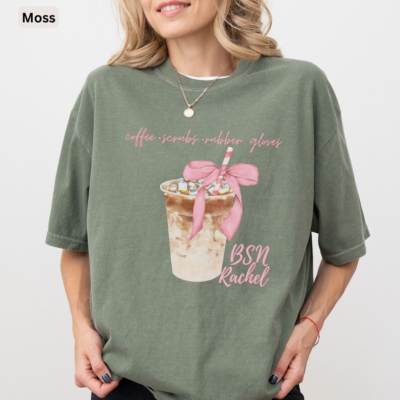 May include: Moss green t-shirt with a graphic of an iced coffee drink with a pink bow and straw. The text "coffee scrubs rubber gloves" and "BSN Rachel" are in pink script.