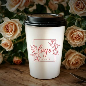 Puede incluir: Vaso de caf&eacute; blanco para llevar con tapa negra. El vaso tiene un logotipo rojo que dice "logo planner" con un dise&ntilde;o floral.