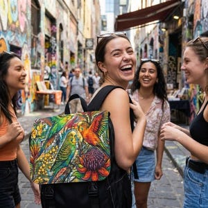 Puede incluir: Una mochila negra con un colorido diseño de loro. La mochila tiene un cierre de solapa y correas ajustables. El diseño del loro incluye colores vibrantes como el verde, el naranja y el amarillo. La mochila la lleva una persona en un entorno urbano.