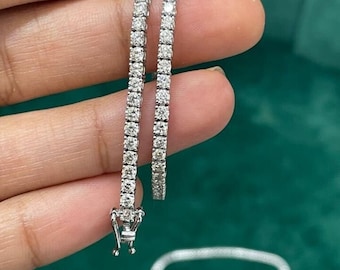May include: Two silver tennis bracelets with small round diamonds set in a pave setting.