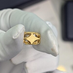 K&ouml;nnte beinhalten: Ein goldener Anh&auml;nger mit einem klaren Stein, der in einem geometrischen Design gefasst ist.