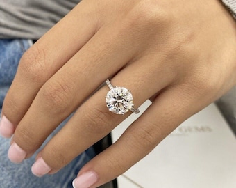 Könnte beinhalten: Ein Verlobungsring aus Weißgold mit einem runden Brillanten und einer Pavé-Diamant-Band.